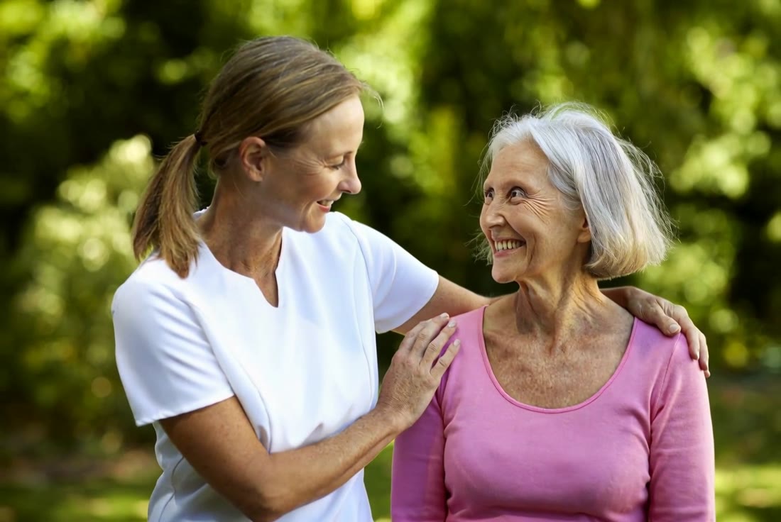 A caregiver and senior smiling together outdoors